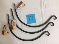 Three black forged metal plant hooks arranged side by side on white cloth, each with mounting hardware attached in plastic bags.