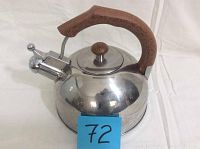 Side view of metal stove top kettle showing wood handle, whistle spout, and reflective surface with minor scratches and discoloration.