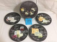 Photo of all four cheese plates showing different cheese and wine designs on each porcelain plate with a blue lot number card