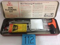 Photo of open metal tin with Outers Gun Cleaning Kit including cleaning rods, bottle of oil, patches, and instructions on lid