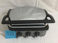 Front side view of the stainless steel griddle grill with three black control knobs and large black handle.