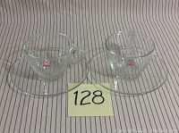 Front view of two Bodum espresso coffee glass cups placed on matching clear glass saucers with a numbered card in front.