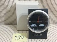 Clock front view showing black face with silver bezel, hour, minute, and second hands, and two small analog gauges for temperature and humidity below the clock face. Brand UniCel DxH 800 and Coulter Cellular Analysis System shown on front.