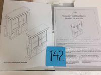 Boxed wall mounted cabinet with assembly instructions on top showing drawings of cabinet with two cupboards and open shelves.