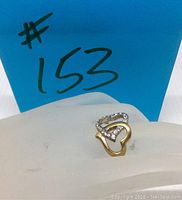 Swarovski double interlock heart ring placed on white platform with blue background marked #153