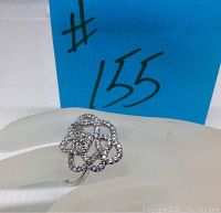 Front and side view of silver tone Swarovski crystal ring showing open floral design and crystal embellishment.