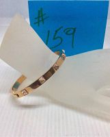 Rose gold tone plated Swarovski Tactic bangle displayed at an angle on a mannequin wrist with visible clear crystal pavé spikes and some scuff marks.