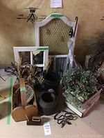 Image showing a variety of home decor items including a metal and wood picture frame, a decorative mirror, woven baskets, artificial greenery, and decorative jugs.