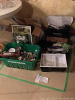 Overview of the paint supplies including a green plastic container holding various items, a paint tray, and some boxed items in the background.