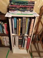 Front view of white 2-shelf wood stand filled with books to show size and structure.