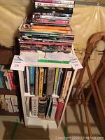 Photo of bookshelf loaded with assorted cookbooks and garden books with DVDs stacked on top and some papers.
