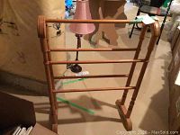 Wood quilt stand with turned wood spindles and horizontal bars for holding quilts, shown in a basement area.