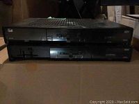 Two black Bell HDTV receivers stacked on top of each other on a cardboard surface.