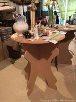 Round particle board knock down table with items on top showing scale and condition.