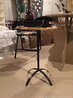 Side view showing the round wood top and black metal tripod base of the small side table.