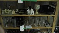 Assortment of ceramic miniature houses, stoneware and glass cups and bowls on shelving