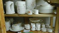 Shelf view showing stacks of plates, bowls and cups with floral decal