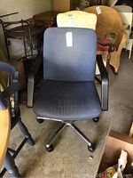 Front view of a blue fabric office chair with black armrests and wheeled base, showing some wear.