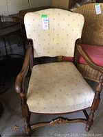 Front view of the adult wooden armchair upholstered in cream fabric with floral pattern and curved armrests.
