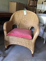 Front view of the natural wicker rocking chair with pink seat cushion.