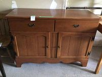 Front view of wooden dining hutch showing drawers and double-door cabinet below, placed on concrete floor.