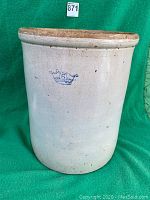 Stoneware crock with blue crown emblem and number 5 on cream exterior against green fabric background.