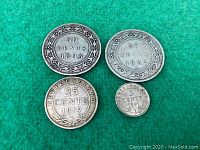 Four silver Newfoundland coins displayed on a green background, denominations and dates visible.