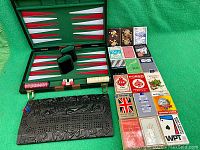 Backgammon set open in green background with chips and dice laid out, 18 decks of playing cards arranged on the side