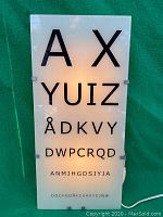 Front view of illuminated eye chart light panel showing all rows of letters from AX down to DOCFGD...
