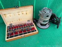 Mastercraft router and open wooden box with 17 router bits inside, displayed on green surface