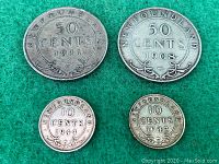 Four Newfoundland silver coins on green felt, front sides with denomination and year visible.