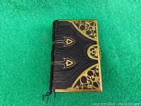 Front cover: black embossed leather with gold-filled corner accents