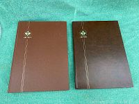 Closed view of two brown Uni-Safe stamp albums with logo and double stripe design on front cover.