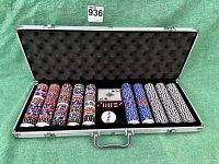 Open poker chip set inside aluminum case showing multiple stacks of colorful plastic chips, two decks of cards, dice, and dealer button.