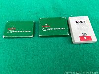 Three boxes labeled Zippo Greenskeeper and a white box labeled Zippo Rule on a green surface.