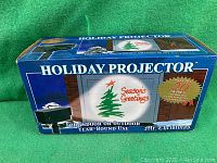 Boxed holiday projector with 'Season's Greetings' and Christmas tree image on packaging