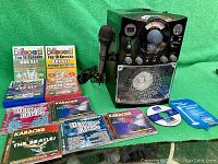 Full lot display showing the Singing Machine karaoke player, various karaoke CD jewel cases, and wired microphone.