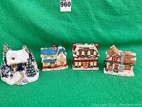 Front view of four vintage Dickens-style miniature houses on green backdrop.