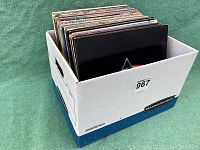 Bankers Box branded box filled with vinyl LP records on green surface
