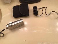 Nikon Coolpix camera with wrist strap and soft black protective case laid on flat surface