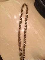 Full view of the gold-tone chain laid flat on a surface showing length and clasp.
