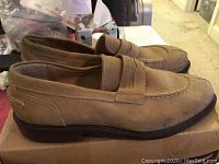 Side view of brown suede men's loafers showing stitch detailing and black sole.