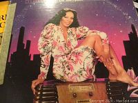 Cover of Donna Summer album showing her sitting in a floral outfit against a cityscape background