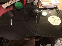 Four vintage 12-inch black vinyl records laid out overlapping on a surface.