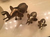 Three brass elephant figurines arranged in descending size order on a light surface.