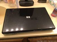 Closed top view of black HP G60-535 laptop showing HP logo on the lid with visible wear and scratches.