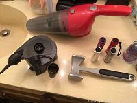 Photo showing the entire lot including red handheld vacuum cleaner, inflatable air pump with three nozzles, metal meat tenderizer, and three lipstick tubes.