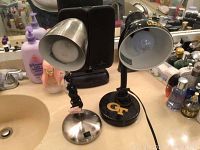 Two desk lamps on a bathroom counter, one metallic silver and the other black with a Georgia Tech logo on the base.