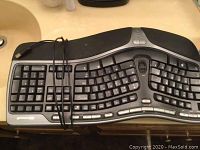 Top view of Microsoft ergonomic keyboard showing split key design with USB wired cable wrapped around