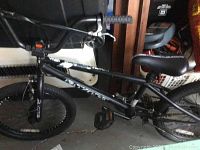 Side view of the black BMX bike showing the frame, seat, pedals, and tires.